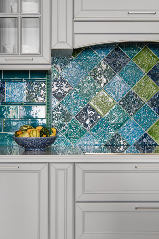 Зону с варочной поверхностью визуально оформили как очаг: ее подчеркнули симметричным расположением шкафов и раскладкой плитки. Для фартука выбрали яркую плитку с богатым орнаментом, напоминающим восточные мотивы.