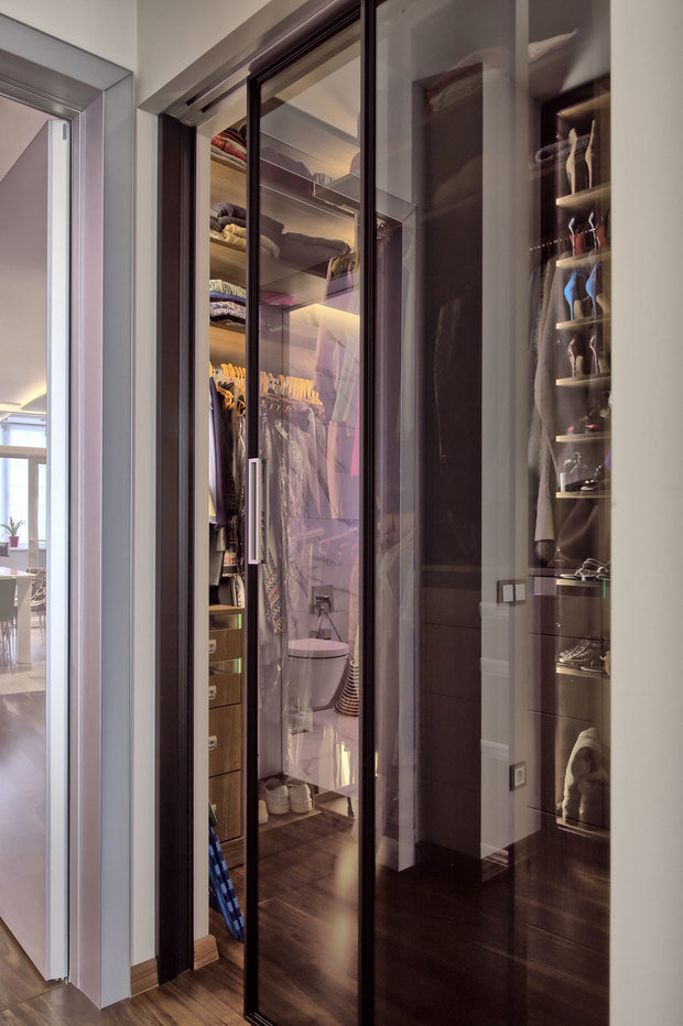Интерьер гардеробной в современном стиле со стеклянными дверцами