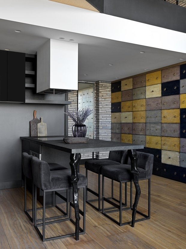 Вертикальные фасады шкафов, которые выполнены в виде уложенных друг на друга выдвижных ящиков, изготавливались вручную по эскизам INRE. Чтобы добиться винтажного эффекта, на дереве механическим способом были сделаны трещины, после чего на поверхность наносилось порядка 14 слоев различных лакокрасочных покрытий, создающих «вековую историю». 