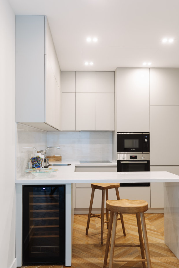 Кухонный остров дополнили деревянными табуретами, которые отлично вписались в интерьер. А винный шкаф хозяйка использует для хранения овощей и фруктов. 