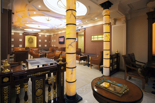 Интерьер офиса в классическом стиле с золотыми колоннами и темной мебелью