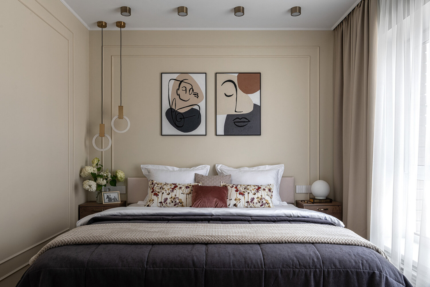 Стены оформлены рамками, характерными для стиля современной классики, в основе которой лежит принцип симметрии. А расположение светильников в зоне кровати и мебели на противоположной стене абсолютно ассиметрично — в духе современных трендов.