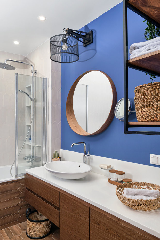 Для ванной комнаты выбрали сапфировый синий оттенок, который отлично сочетается с мебелью цвета ореха. Хозяйка хотела открытое хранение
для полотенец: организовали подвесной стеллаж и поставили плетеные корзиночки.