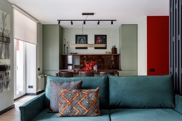 На кухне отказались от верхних шкафов и вытяжки: эта зона совсем не выглядит рабочей и не создает ощущение, что ты находишься весь день на кухне. Для более уютной обстановки над кухонным островом повесили низкий светильник. 