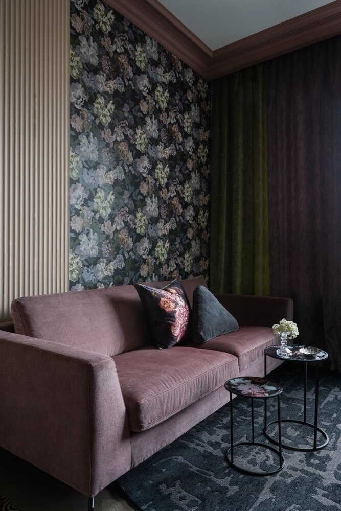 В квартире нет ни одного простого, открытого оттенка, все они с сероватым сложным подтоном. Дымчатый оттенок пола в инженерной доске, выложенной английской елочкой, перекликается со вставками из шпона сегментарной выклейки на фасадах тумбы напротив дивана.