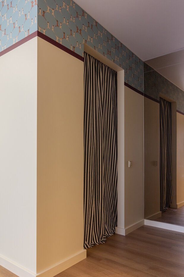 На стене рядом с гардеробной  разместили тонированное зеркало, которое дополнительно отражает свет от единственного окна в квартире.