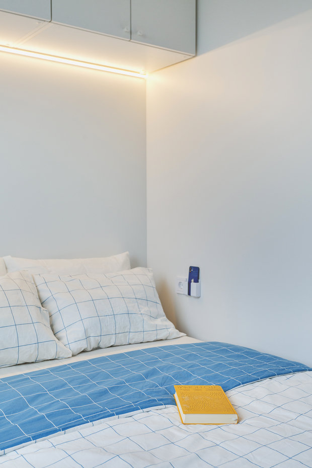 Кровать придвинута к стене, пользоваться прикроватной тумбой может с комфортом только один человек. А если жильцов двое, то гаджеты заряжать и ставить будильники уже неудобно. Решили эту проблему с помощью дополнительной розетки и кармашка для телефона.