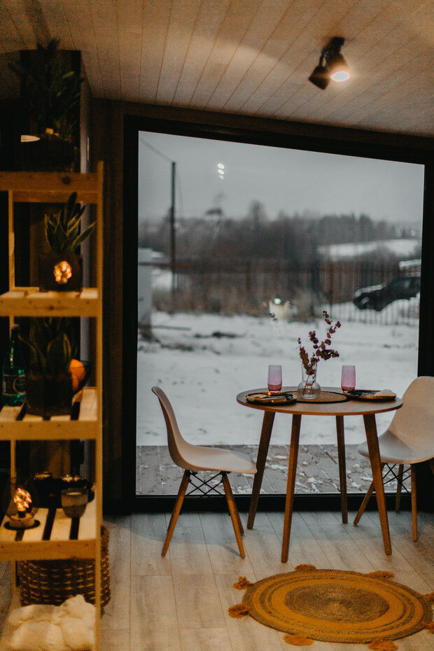 Около одного окна обустроили уютную столовую зону с круглым обеденным столиком и стульями. Летом мебель можно перенести на открытую веранду.