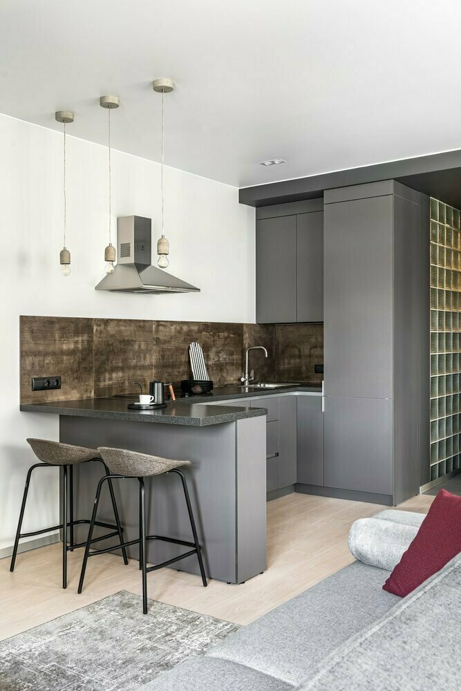 Кухня имеет стандартный набор бытовой техники: холодильник, мойка, варочная поверхность, духовой шкаф, вытяжка. От верхних шкафов по одному из фронтов кухни решили отказаться ради ощущения большего простора. Форма кухни в виде буквы П позволила организовать небольшую зону для завтраков. Все модули стандартных размеров, но сам гарнитур изготавливали на заказ. Кухня имеет стандартный набор бытовой техники: холодильник, мойка, варочная поверхность, духовой шкаф, вытяжка. От верхних шкафов по одному из фронтов кухни решили отказаться ради ощущения большего простора. Форма кухни в виде буквы П позволила организовать небольшую зону для завтраков. Все модули стандартных размеров, но сам гарнитур изготавливали на заказ.