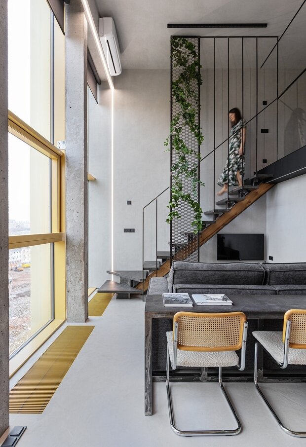 Металлическую обвязку окон и решетки внутрипольных радиаторов отопления выкрасили в желтый оттенок, также предусмотрели закрытые розетки в полу. Несущие столбы оставили в бетоне.