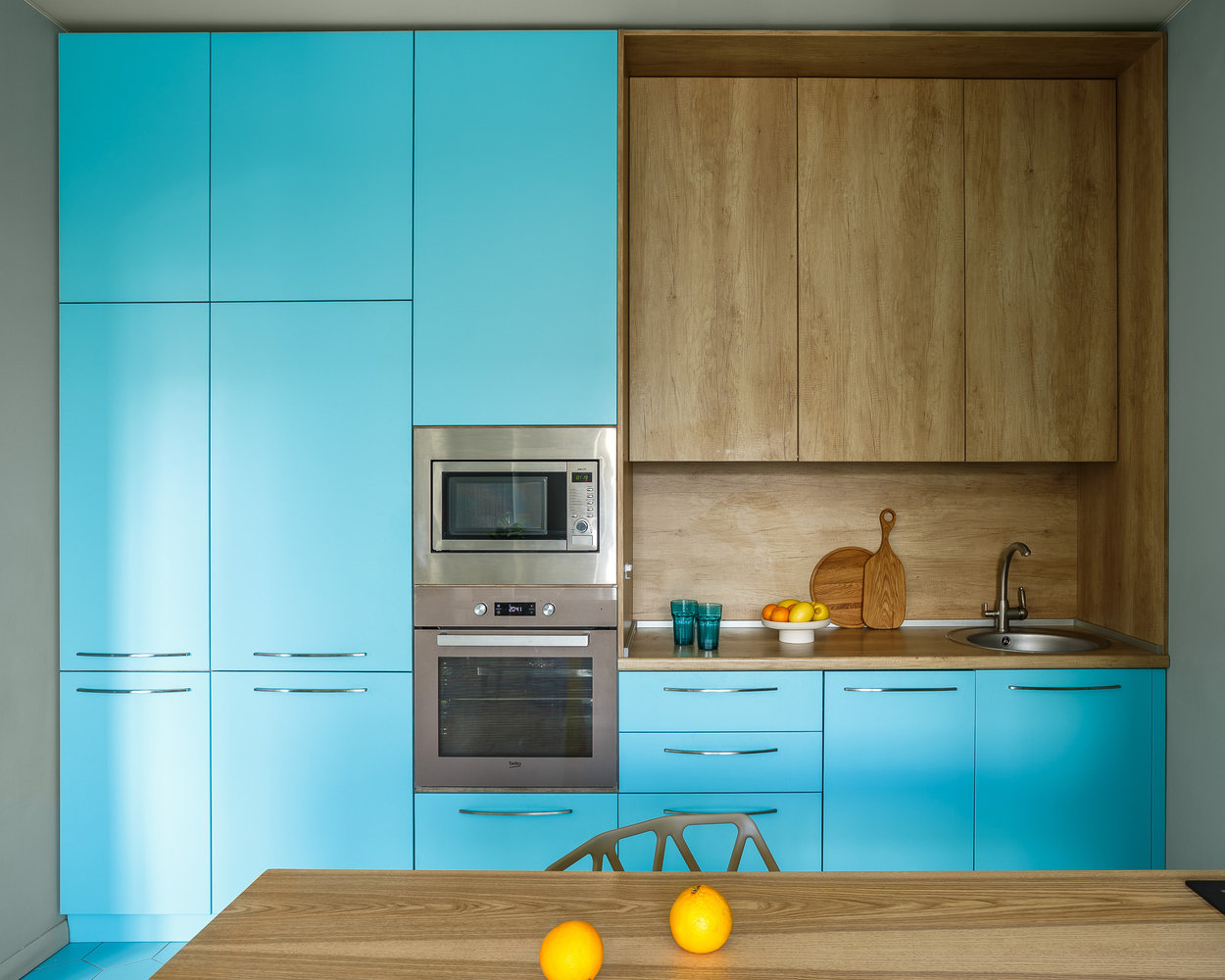 Кухонный гарнитур изготавливали на заказ у местных мастеров. СВЧ и духовой шкаф встроили в пенал друг над другом. Рядом встал встроенный холодильник. Хранение в шкафах предусмотрели до потолка, для большей вместительности.