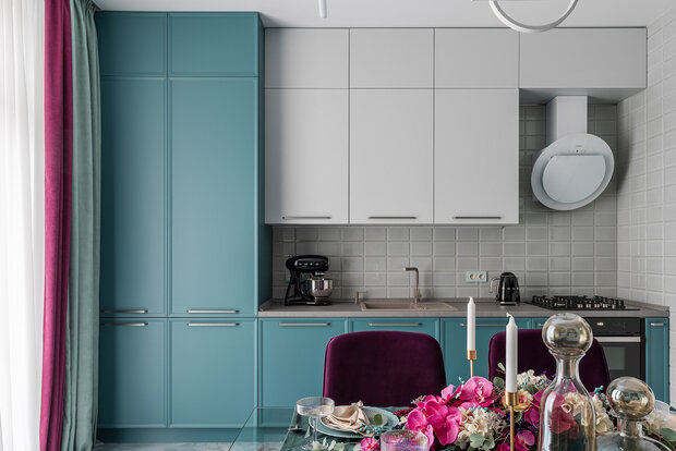 Кухонный гарнитур выполнили в двух цветах: цвет морской волны и белый. Кухонный фартук выложили до потолка.