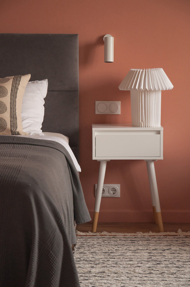 В спальне акцентом стал терракотовый цвет стен, поэтому мебель, текстиль и декор подобрали в нейтральных бежево-серых оттенках. Кресло в спальне подобрано в цвет стен.