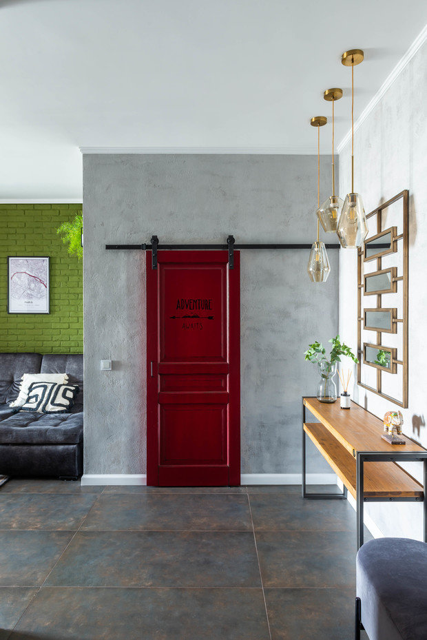 Красная амбарная дверь ведет в гардеробную. Ее сделали самостоятельно: в «Леруа Мерлен» купили обычную деревянную дверь, покрасили ее в столярном цехе. Причем перекрашивали неоднократно до получения необходимого оттенка. После художник сделал на двери роспись на тему путешествий.