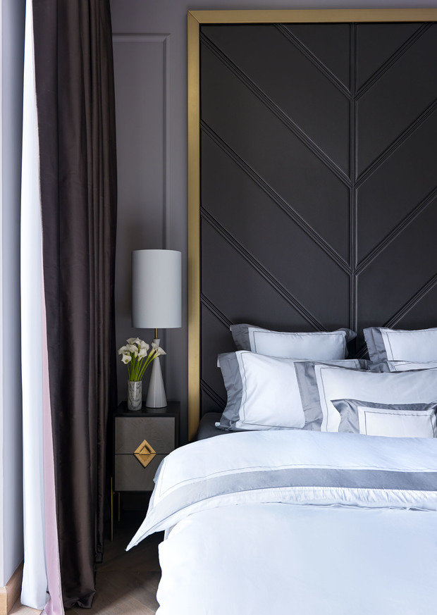 Изголовье по форме перекликается с рисунком напольного покрытия и обрамлено латунной рамой.