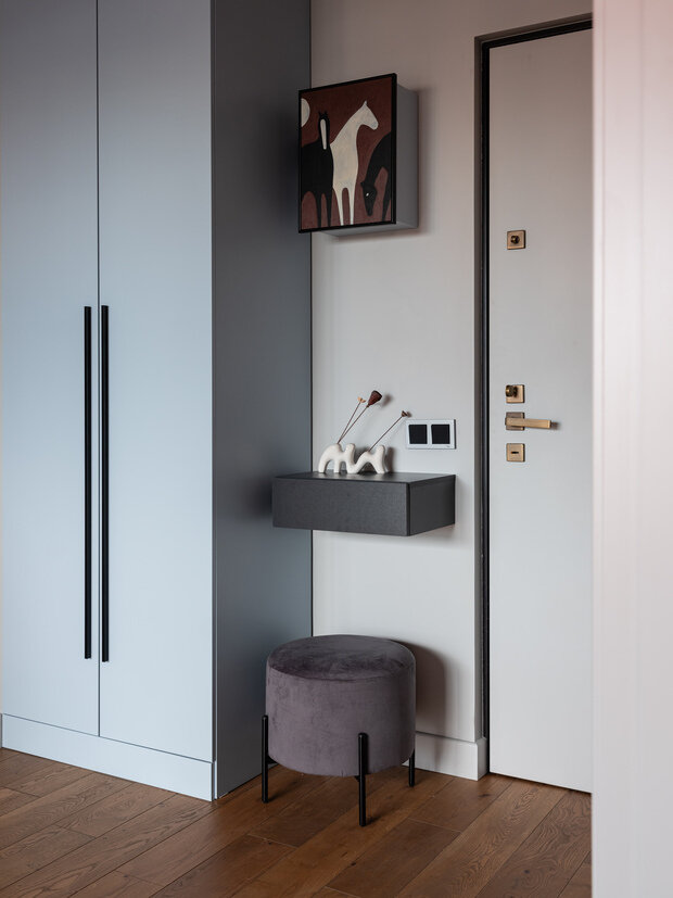 Входная дверь изнутри выкрашена в цвет стен. Электрощиток спрятали в короб, изготовленный на заказ в цвет мебели, с закрепленной на дверце картиной художницы — так абсолютно технический момент превратился в арт-объект.