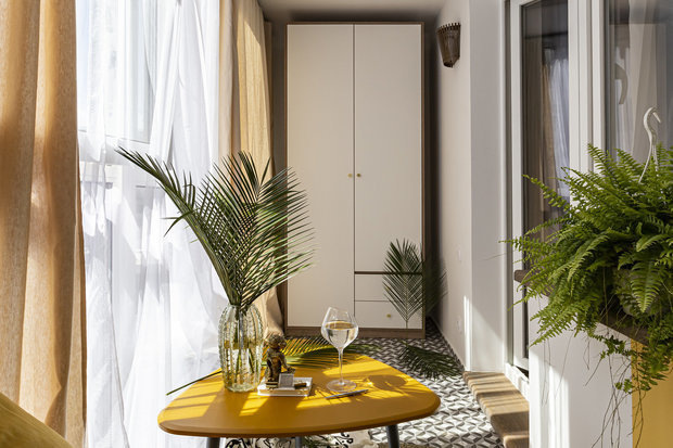 Интерьер балкона в стиле минимализм с желтым столиком и растениями