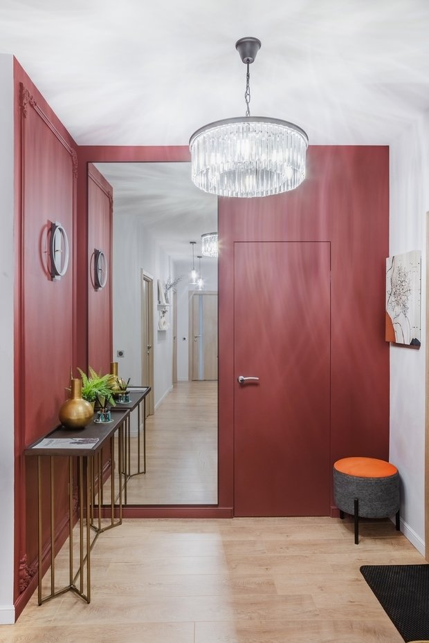 За картиной в прихожей спрятали электрический щиток. Дверь в гардеробную выбрали со скрытой установкой и выкрасили в акцентный цвет.