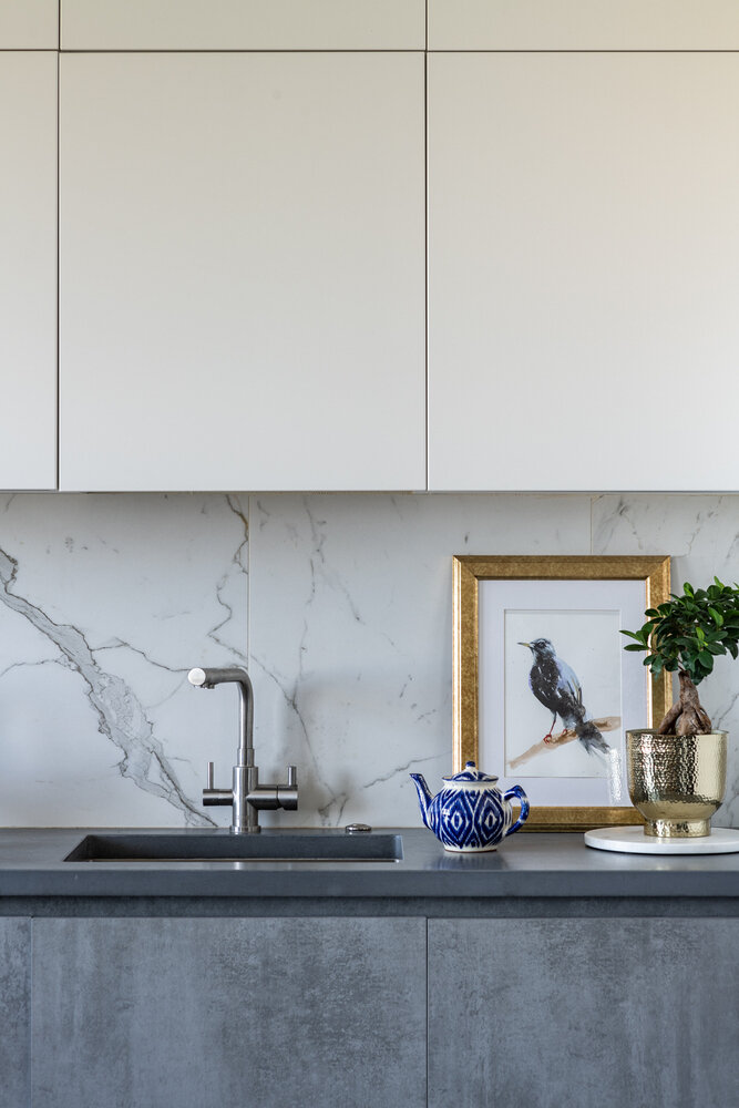 Для столешницы использовали архитектурный бетон. Этот материал — не самое распространенное решение, но он обладает отличными эксплуатационными характеристиками. Он устойчив к горячим поверхностям, меньше царапается по сравнению с искусственным камнем. А если и появляются царапины, то выглядят они очень органично, создают «живую» текстуру. Его можно реставрировать и шлифовать при необходимости.