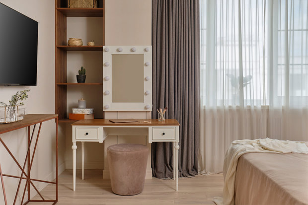 На полу — инженерная доска из ясеня. Около окна поставили милый туалетный столик и стеллаж для хранения дамских аксессуаров в плетеных
корзинках. Телевизор разместили над консолью напротив кровати.