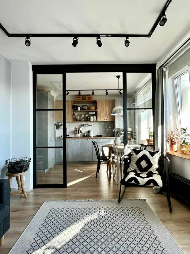 Для обеденной зоны выбрали круглый стол в шпоне, разные деревянные стулья и подвесной светильник.