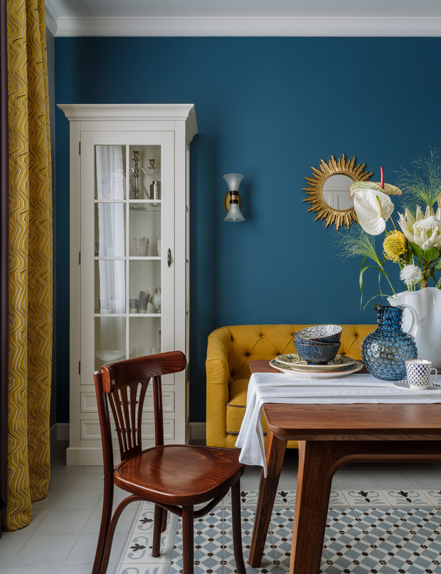 Площадь кухни позволила разместить здесь полноценную столовую зону с обеденным столом, стульями и небольшим диванчиком. Места хватило и для красивых буфетов.