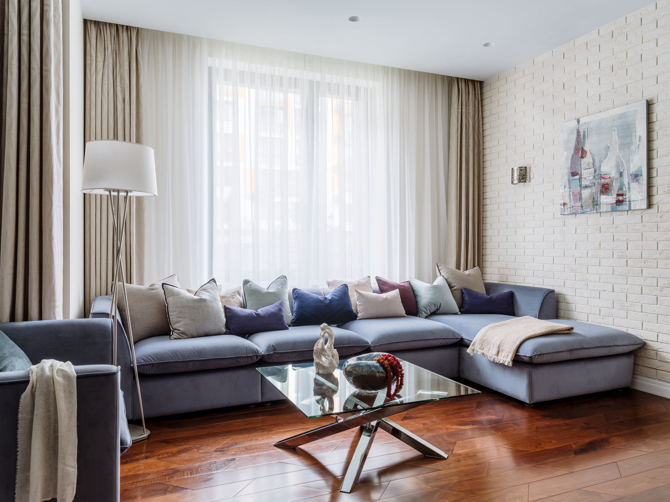 Одну из стен в гостиной выложили гипсовой плиткой под кирпич и плотно закрасили краской. Остальные стены покрасили глубоко матовой краской RAL 1013 с легким песчаным оттенком.