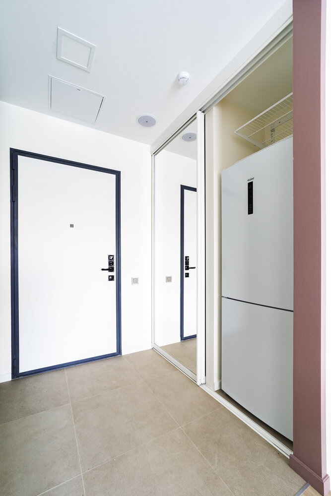 Необычным стал выбор места для размещения холодильника — он расположен в нише за раздвижной зеркальной дверью. Это позволило сэкономить бюджет и приобрести отдельно стоящую модель, а также убрать холодильник из основной зоны кухни-столовой.