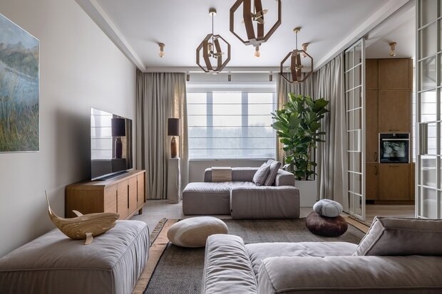 В каждом помещении было сделано минимум по два сценария освещения, чтобы характер пространства менялся в зависимости от того, какой свет включен. По центру гостиной висят деревянные светильники разной высоты.