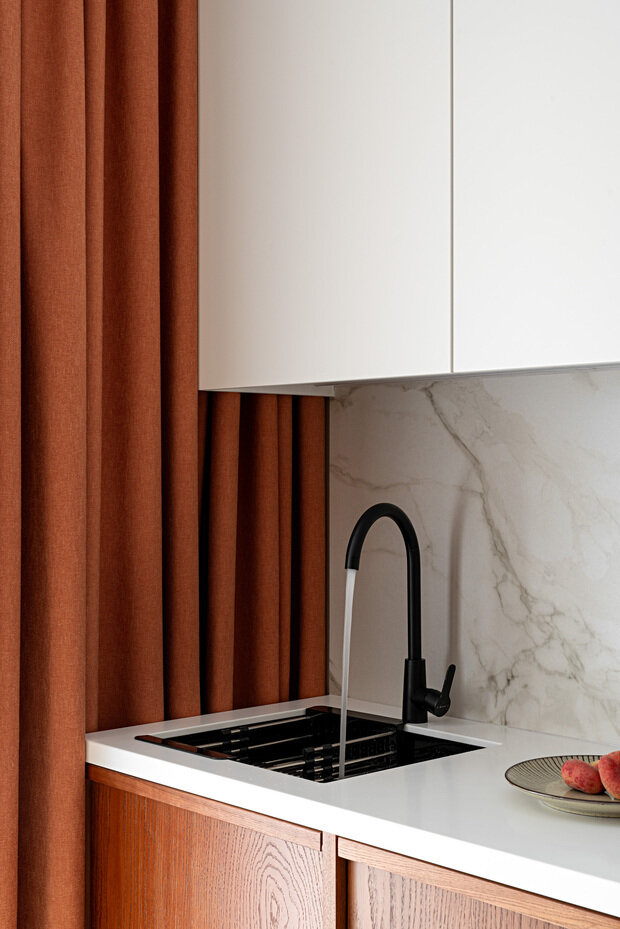 Вся корпусная мебель выполнена в шпоне дуба, а верхние кухонные фасады в эмали. Столешницы из белого акрилового камня.