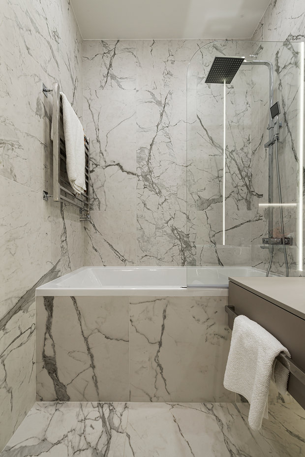 Отделка стен и пола санузлов выполнена с помощью керамогранита 1200×600 мм с текстурой белого мрамора.