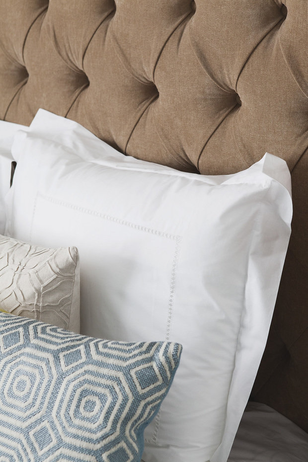 Интерьер спальни в классическом стиле с мягким изголовьем и декоративными подушками
