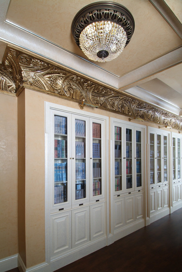 Интерьер гардеробной в классическом стиле с белыми шкафами и золотой лепниной