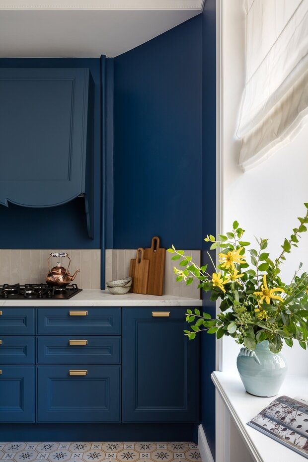 В кухне римские шторы из полупрозрачной ткани подчеркивают молдинг по периметру окна.