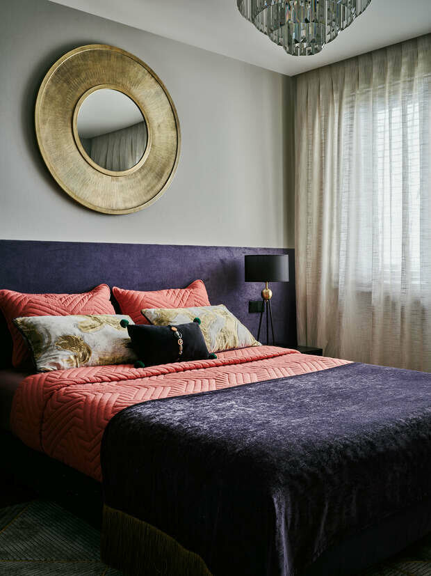 Главным акцентом кровати служат роскошные подушки из золотого жаккарда от Pierre Frey. Прообразом паттерна стала японская каллиграфия. Они идеально сочетаются с зеркалом над кроватью и придают спальне совершенно уникальный вид. В развитие черничной темы кровать декорирована раннером (дорожкой) из шенилла, отороченным по краям длинной золотой кисеей.