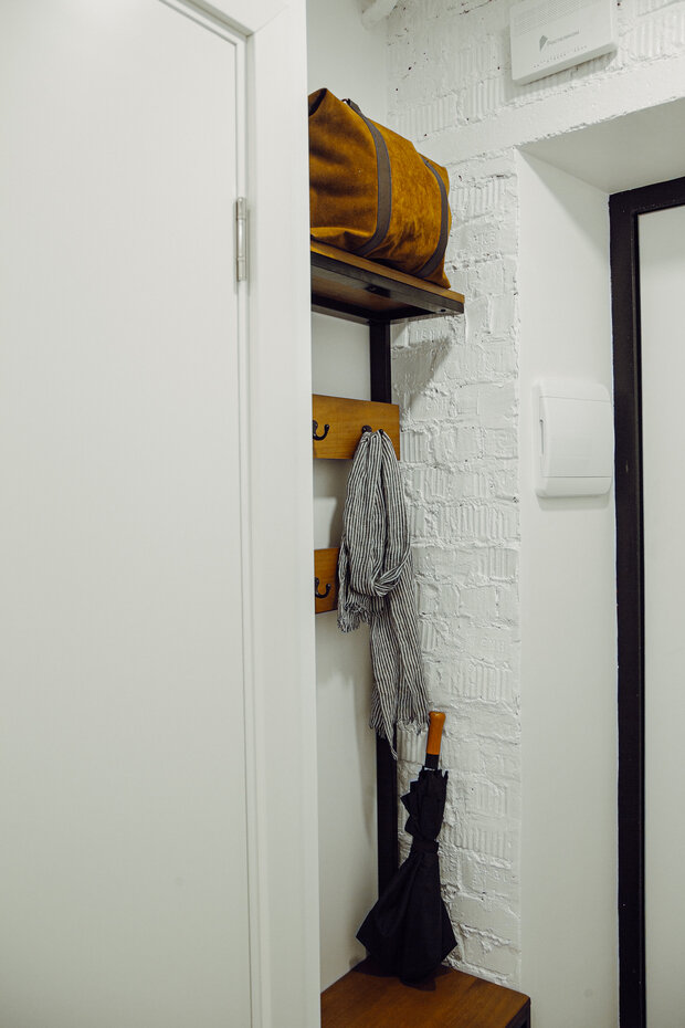 При входе в квартиру предусмотрели небольшую нишу с пуфом и полками с крючками. 