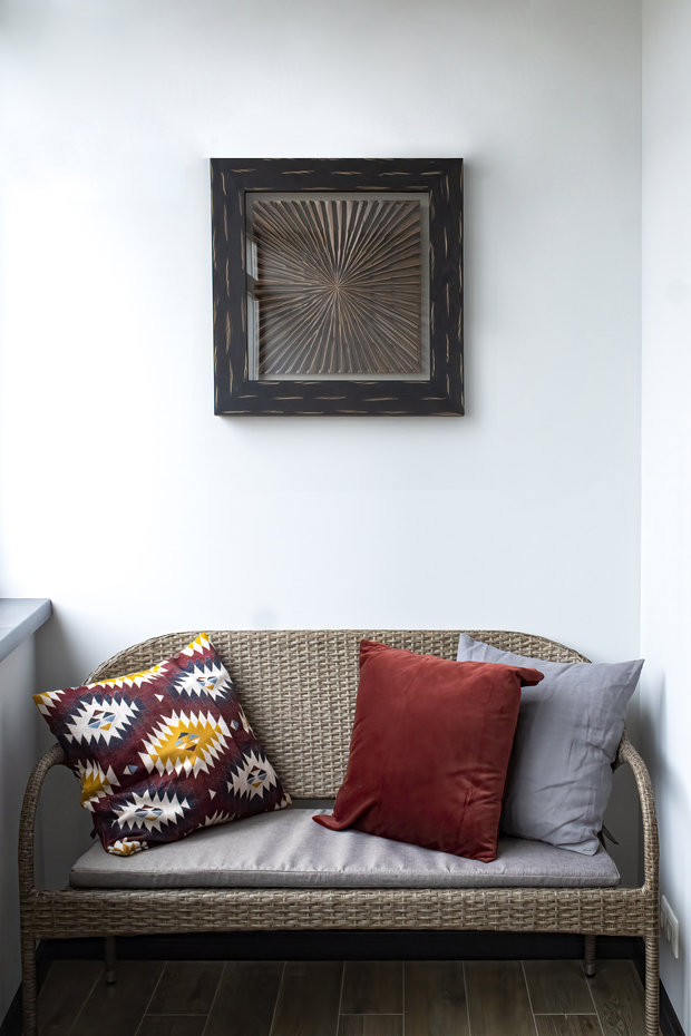 На утепленном балконе разместили всего одну подушку с ярким контрастным скандинавским рисунком: она оказалась очень уместна и дополнила уютную зону с плетеным диванчиком и этническим декором на стене.