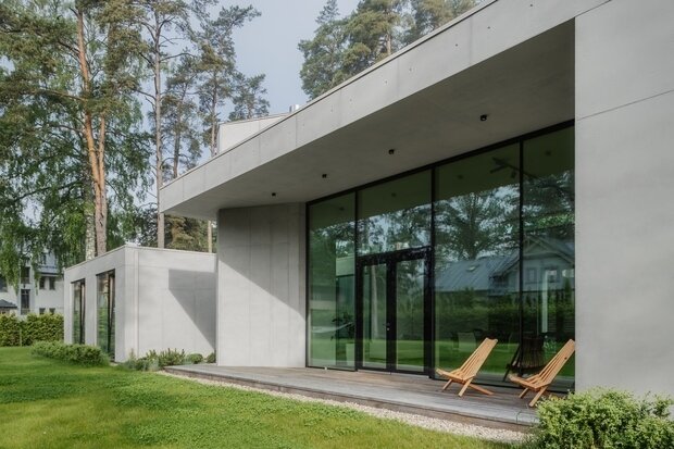 Центральная общественная часть контрастирует с монументальными объемами спальных помещений: динамики ей добавляют консольные кровельные свесы и вертикаль каминной трубы.