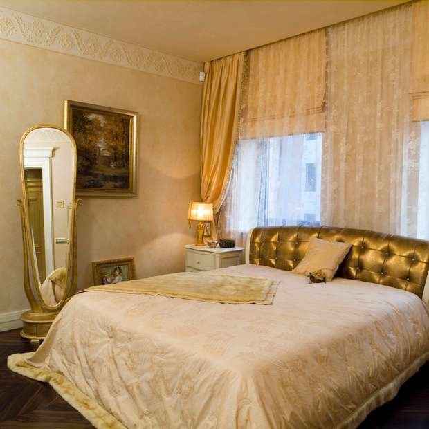 Интерьер спальни в классическом стиле с золотой кроватью и зеркалом