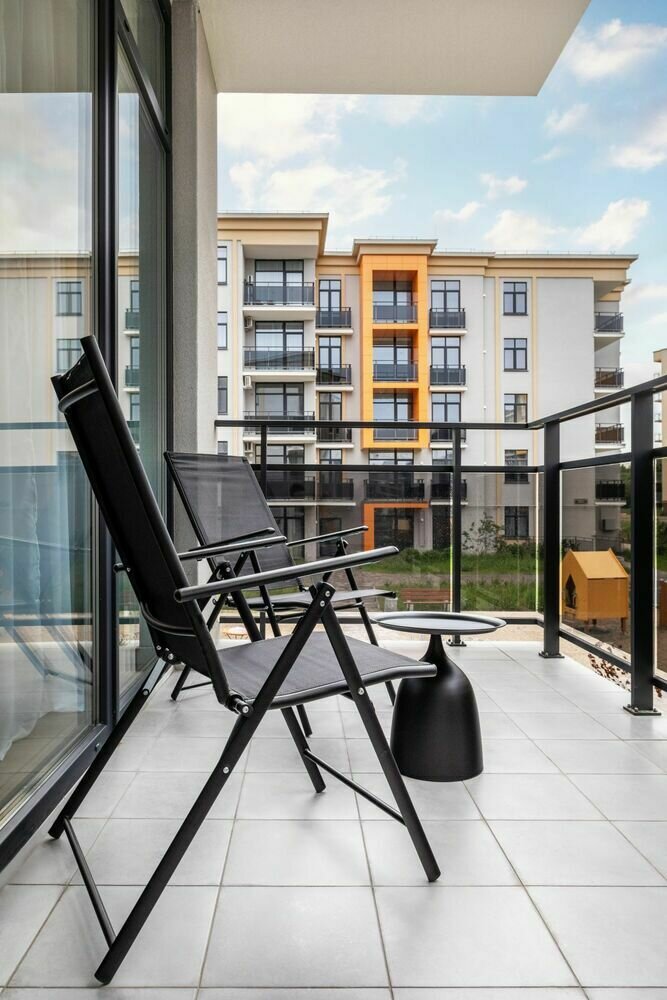 С гостиной есть выход на открытый балкон — на нем обустроили комфортную зону отдыха.