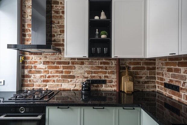 Дом, в котором находится квартира, построен в 1958 году и выполнен из кирпича, дизайнерам хотелось интегрировать оформление фасада и общую эстетику в интерьер, поэтому фартук на кухне выложили плиткой из исторического кирпича.