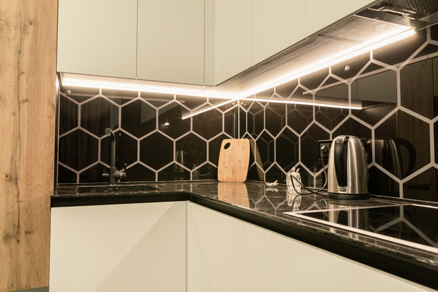 Интерьер кухни в современном стиле с черной плиткой и белыми фасадами