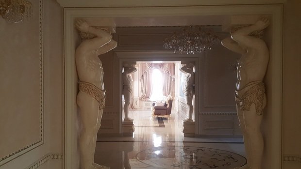 Интерьер гостиной в классическом стиле с атлантами и люстрой