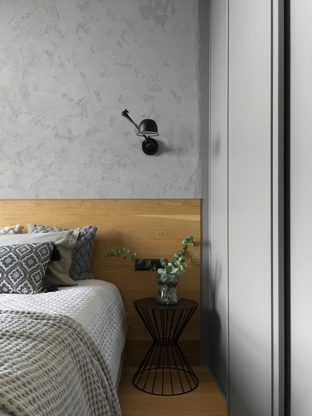 В спальне черные бра и ажурные столики, выполняющие функцию прикроватных тумб, выгодно выделяются на фоне дерева. 