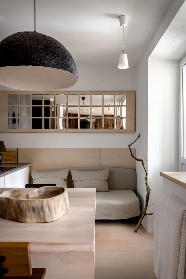 Тиковое блюдо для фруктов служит выразительным акцентом в интерьере, его привезли из Индонезии, в поддержку ему нашли фактурную лесную корягу. Над столом висит абажур-полусфера, камерно освещающий обеденную группу.