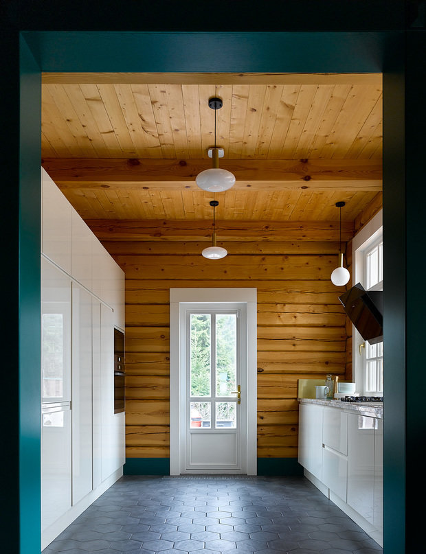 Кухня носит функциональный характер. В ней только готовят. Два функциональных блока расположены параллельно вдоль стен. С одной стороны высокие шкафы с местами для хранения продуктов, выдвижной секцией для бутылок и встроенной техникой: холодильник, морозильник, духовой шкаф. С другой стороны — у стены с окнами — рабочая поверхность с раковиной и газовой панелью.