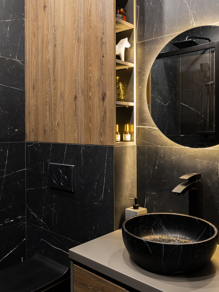 На стенах использовали темный большеформатный керамогранит 120×60 см, на пол уложили керамогранит под дерево. И один в один подобрали по тону дерево на мебельных фасадах.