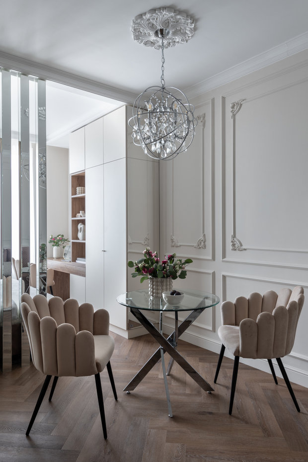 В зоне столовой разместили два красивых кресла, а стол подобрали с металлическими ножками и стеклянной столешницей, чтобы растворить мебель в интерьере.