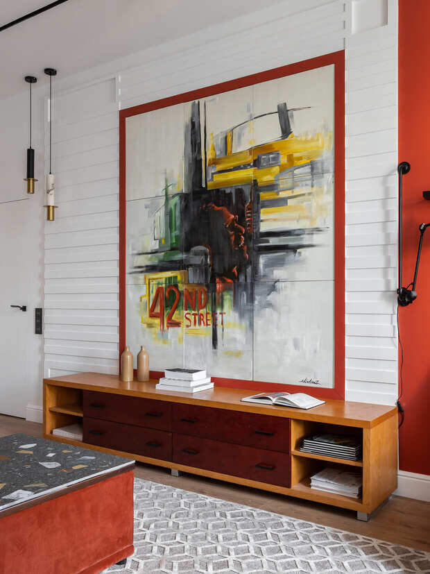 Интерьер гостиной в стиле эклектика с большой картиной и деревянным комодом