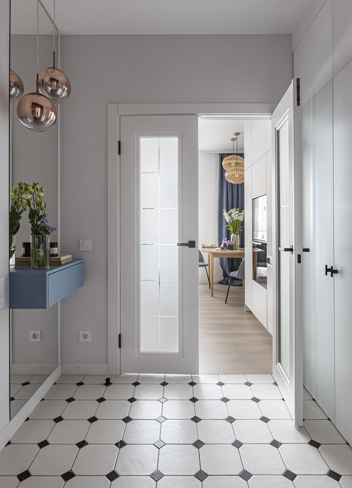Двери со светлыми стеклами между прихожей и комнатой пропускают естественный свет в прихожую, благодаря этому решению в помещении прихожей остается светло, даже когда не включен основной свет.